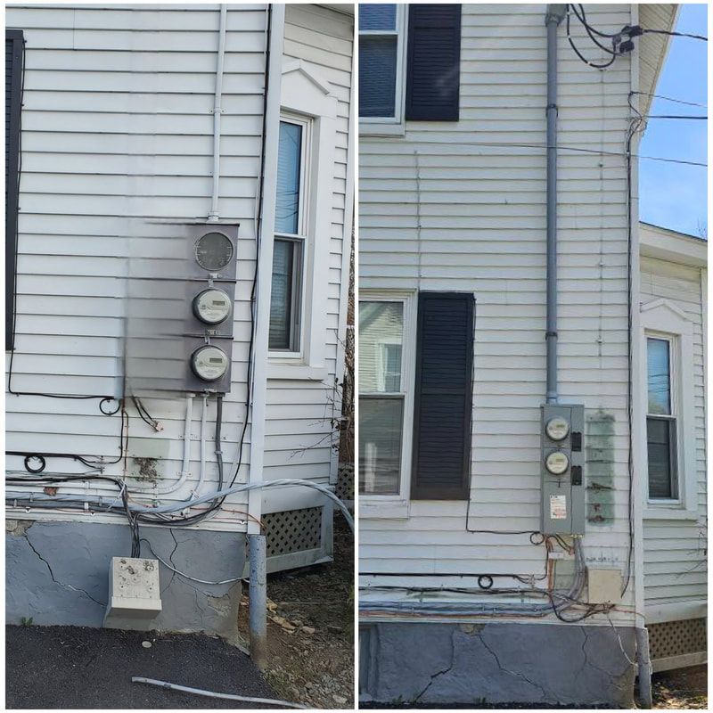 Two white houses with electrical meters and wiring on their exterior walls.