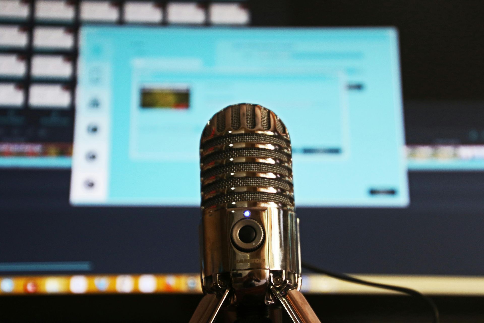 Silver microphone in front of a computer screen displaying audio editing software.