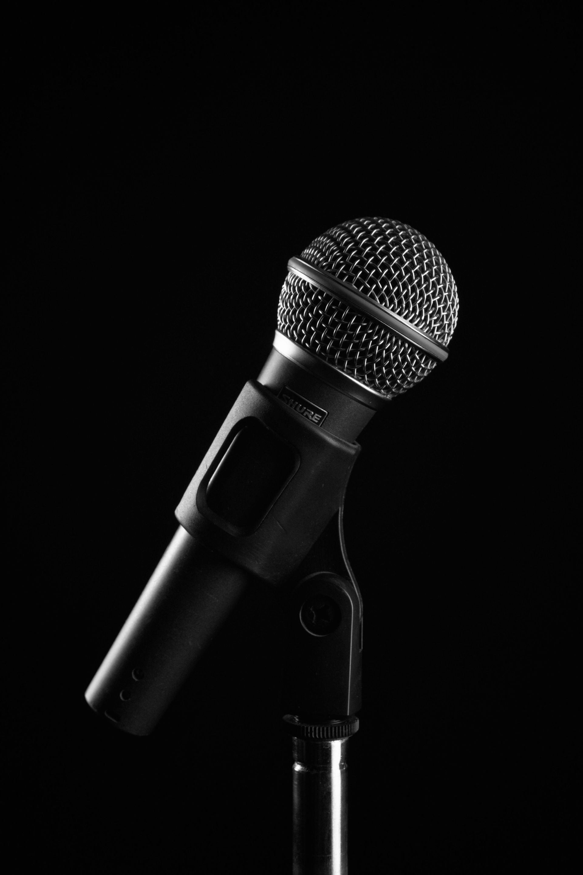 Microphone on stand, black and white photo against black background.