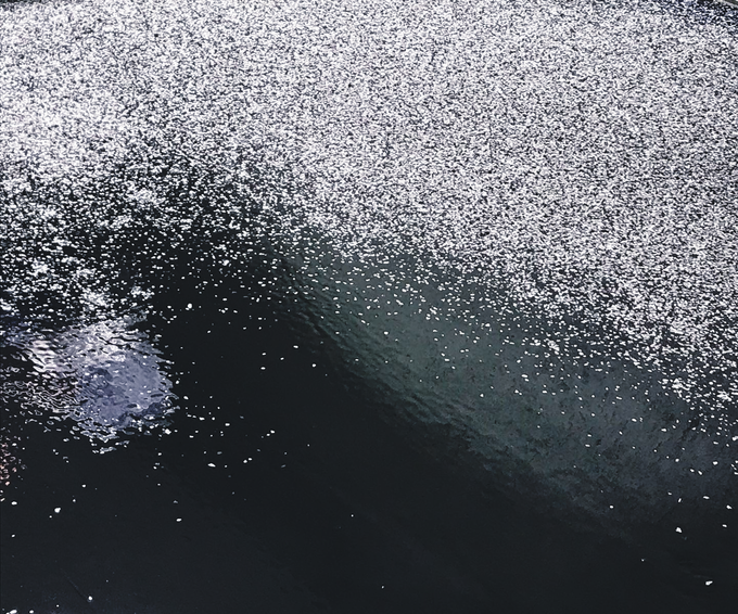 A close up of a wave in the ocean with bubbles coming out of it