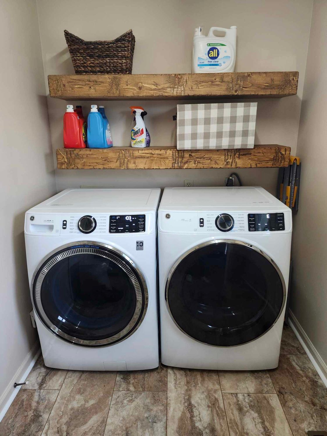White corner shelves holding office supplies and decor; tan and blue binders, plant in silver pot, woven basket. White corner shelves holding office supplies and decor; tan and blue binders, plant in silver pot, woven basket.