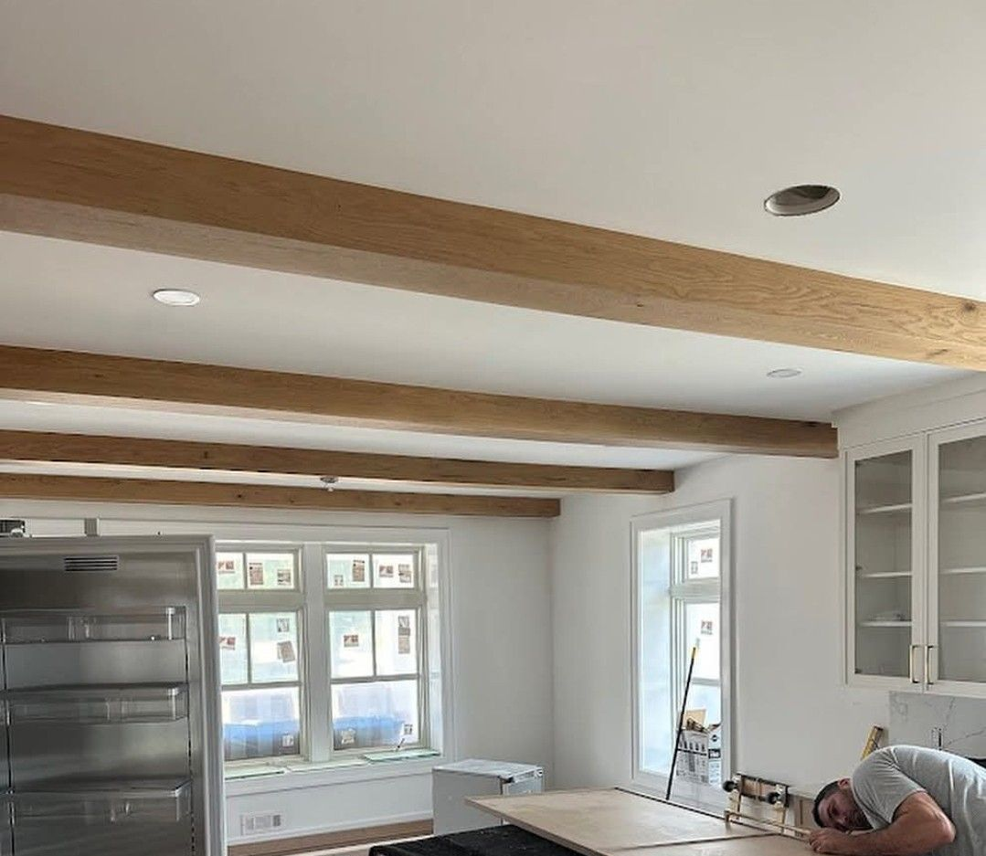 Person in red jumpsuit hammering ceiling studs, standing on a wooden scaffold in an unfinished room. Person in red jumpsuit hammering ceiling studs, standing on a wooden scaffold in an unfinished room.