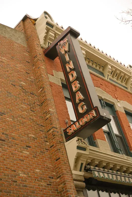 A windbag saloon sign hangs from the side of a brick building