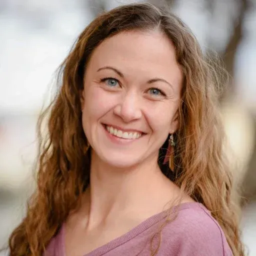 A woman in a purple shirt is smiling for the camera.