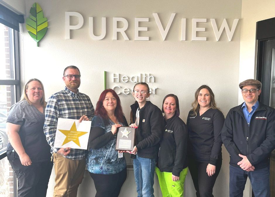 A group of people are standing in front of a sign that says pureview health center, holding an award