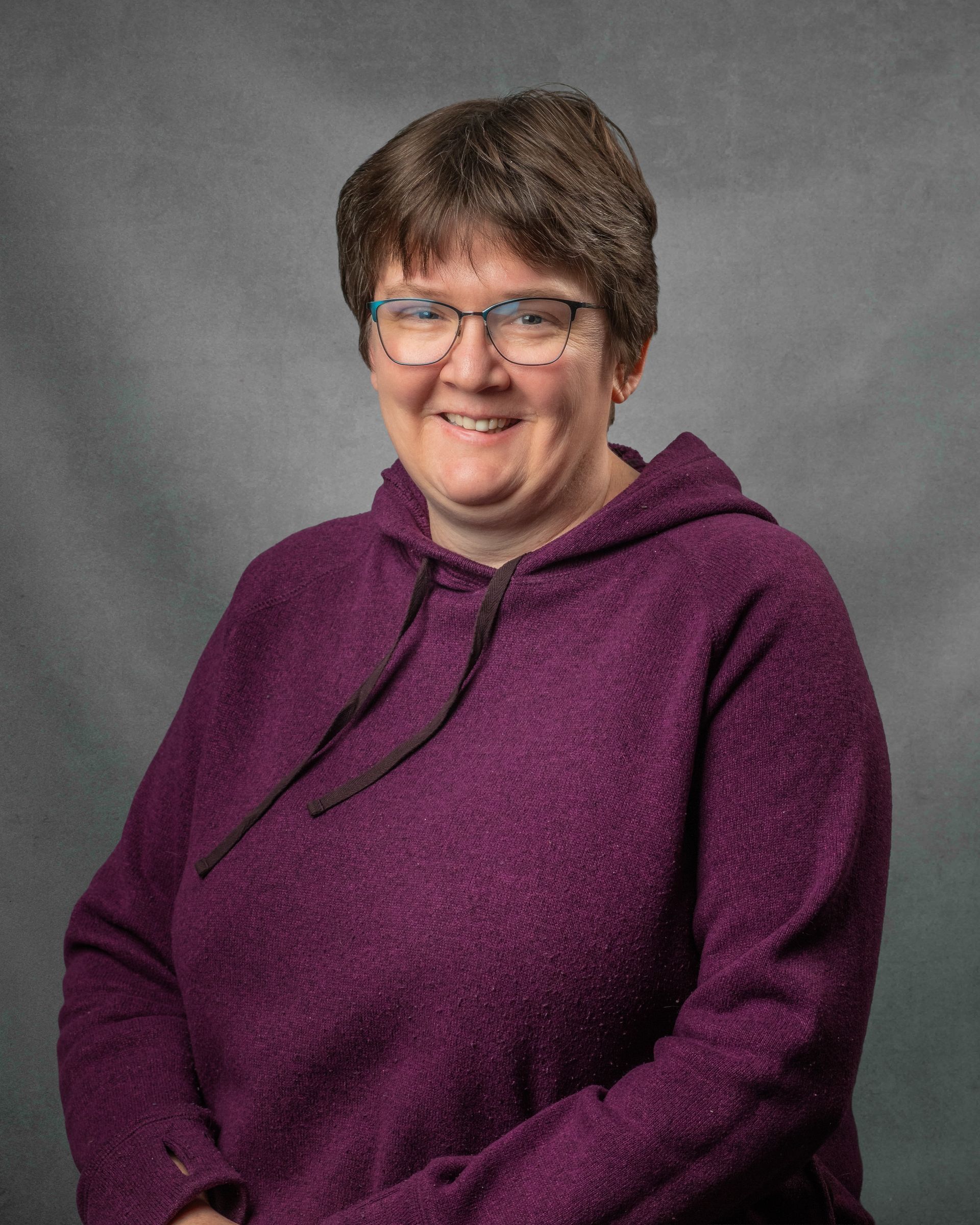 A woman wearing glasses and a black shirt is smiling for the camera.