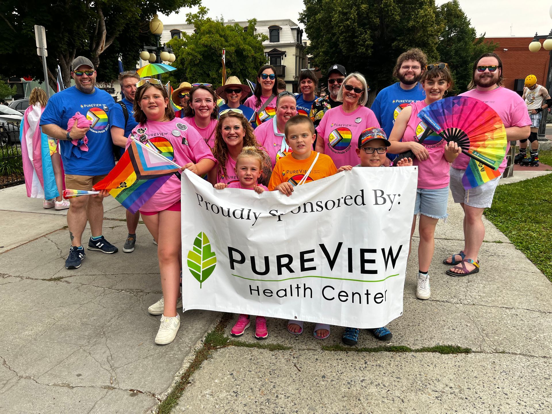 A group of people are standing on a sidewalk holding a banner that says pureview health center.