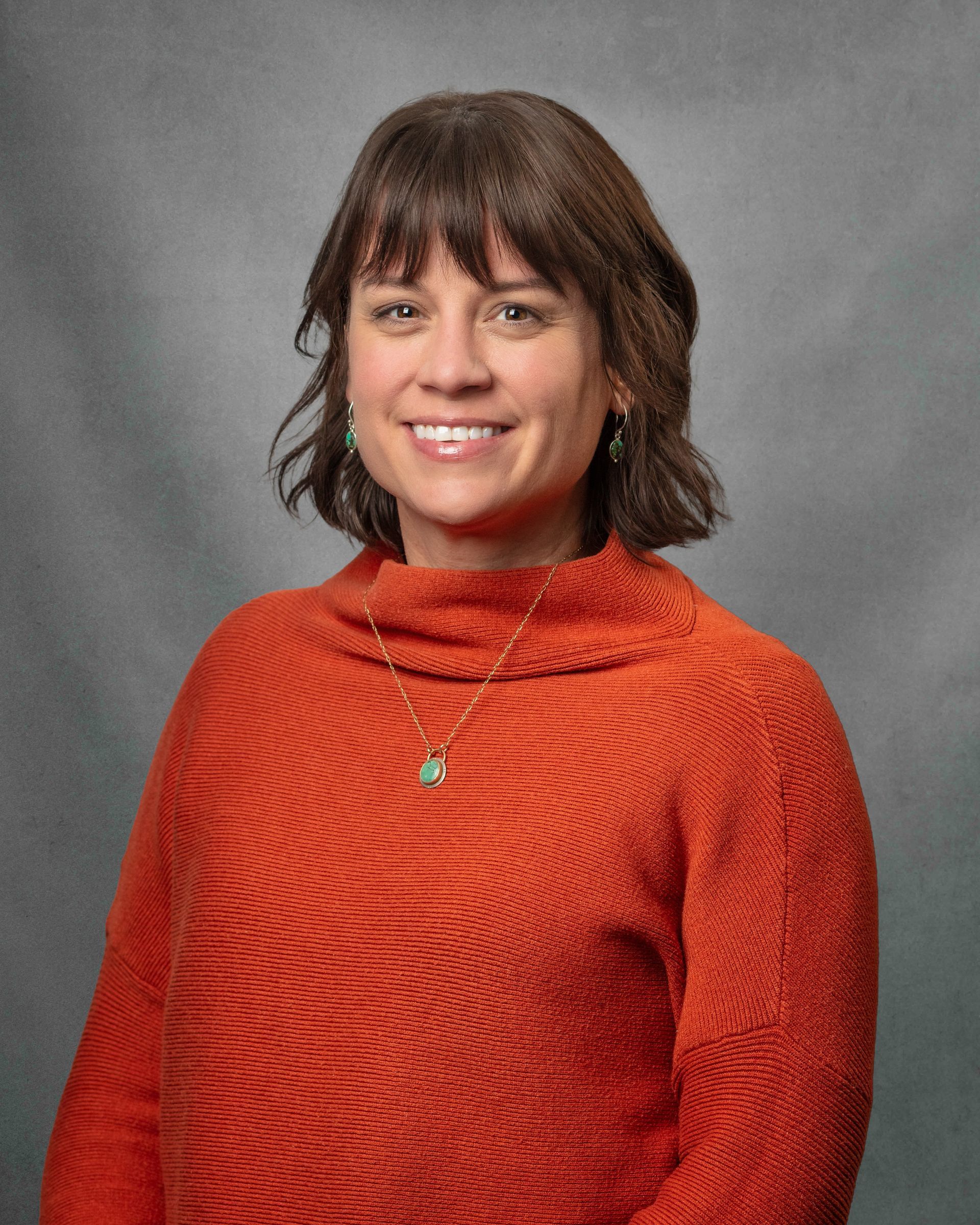 A woman in a red turleneck with a gray background.
