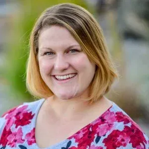 A woman in a floral shirt is smiling for the camera.