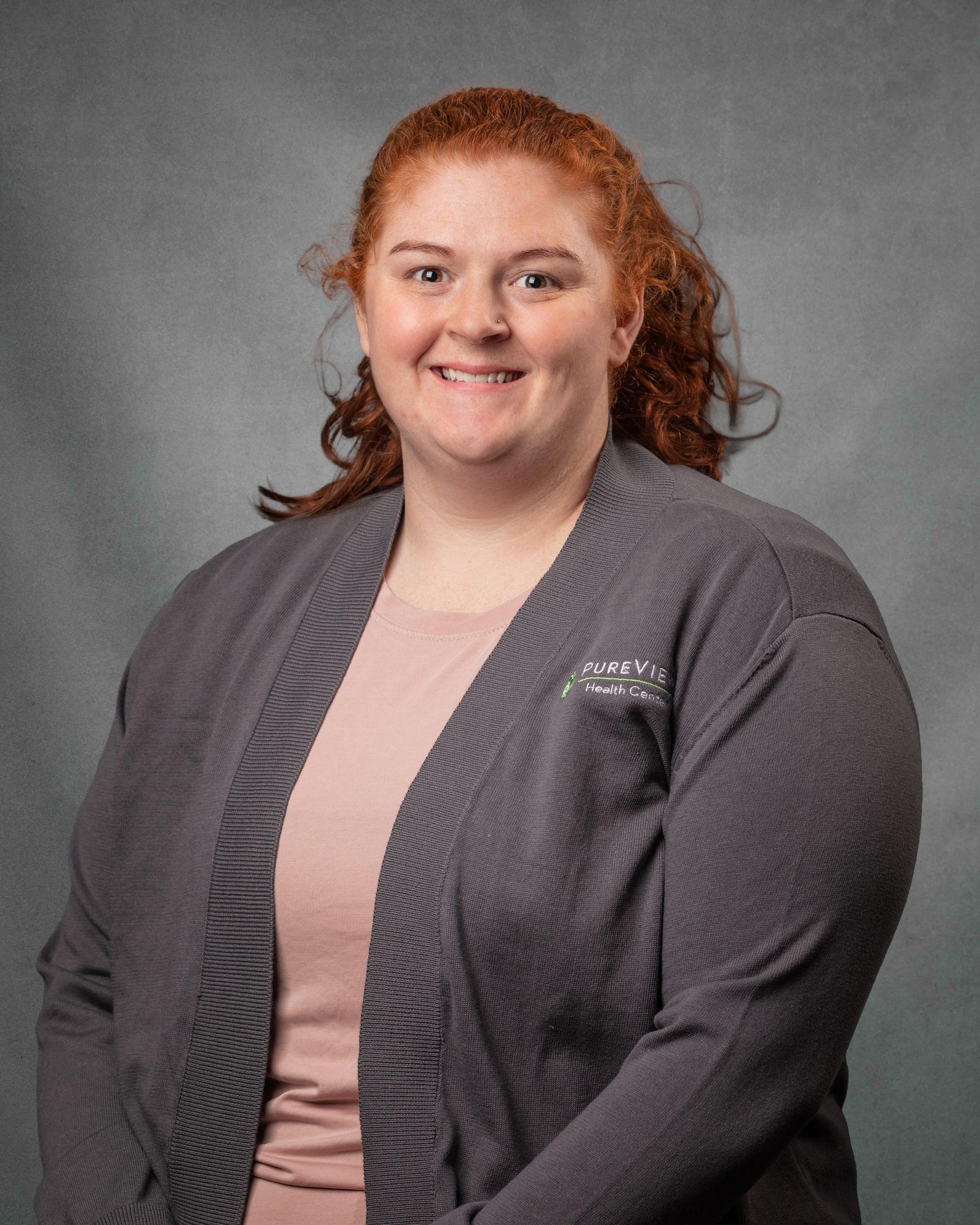 A woman with red curly hair and freckles is smiling for the camera.