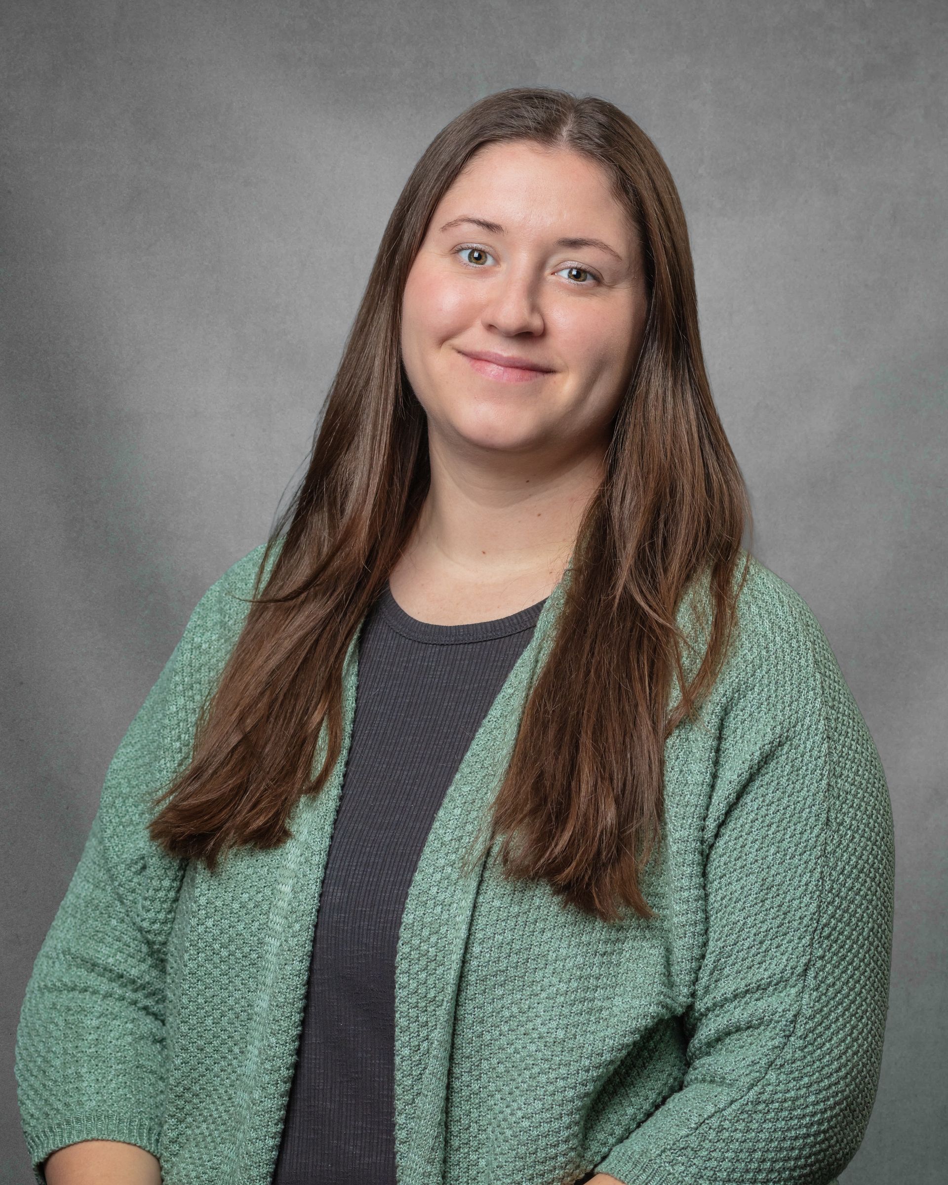 A woman wearing a green cardigan is smiling for the camera.