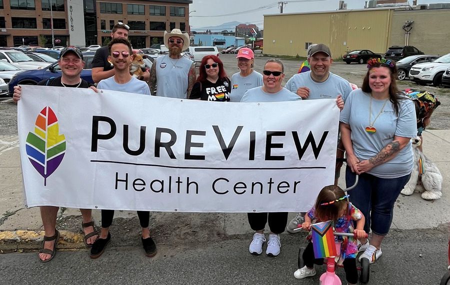 A group of people are holding a banner that says pureview health center.