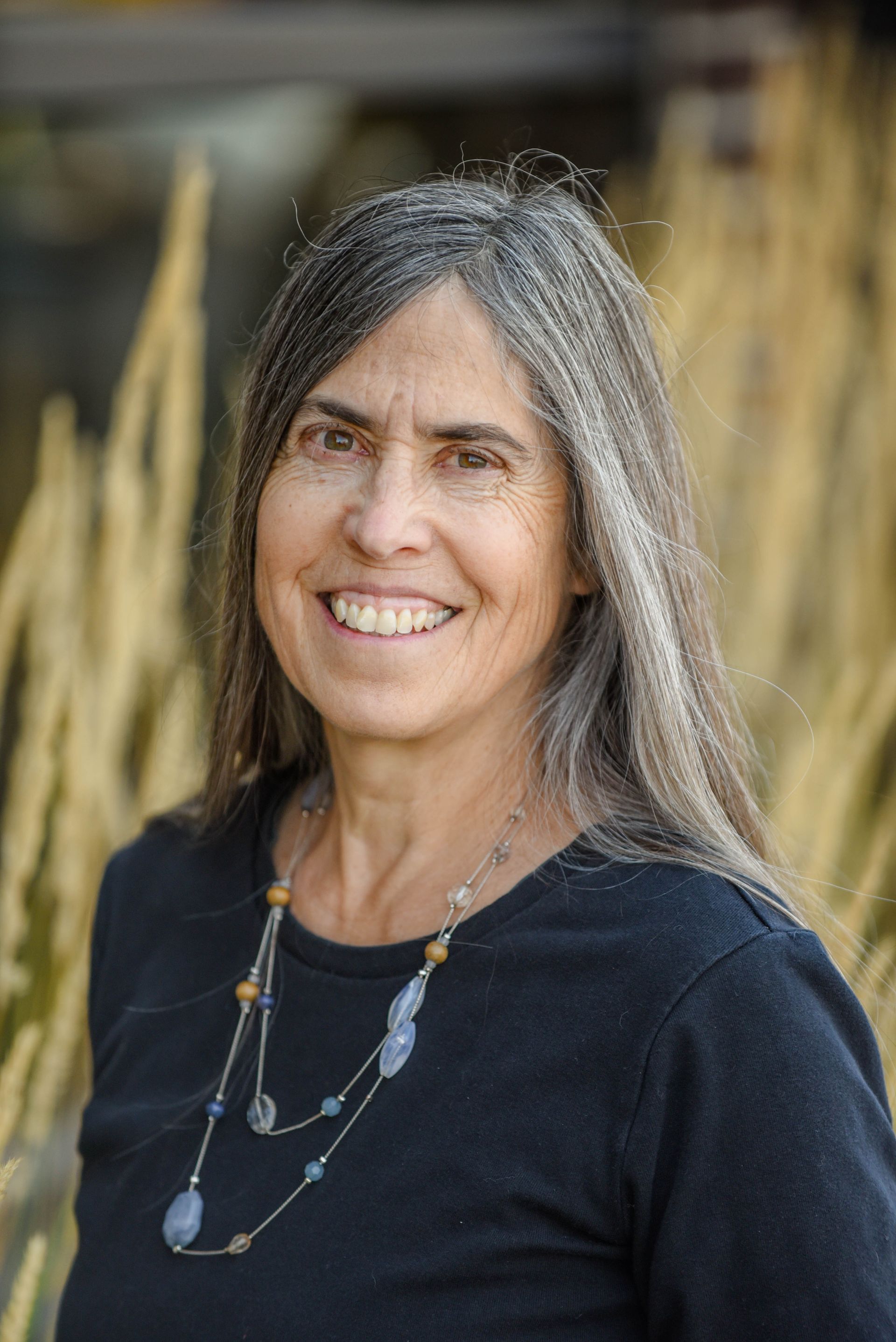 A woman in a colorful jacket is standing in front of a building.