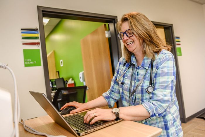 A woman is typing on a computer, smiling. 