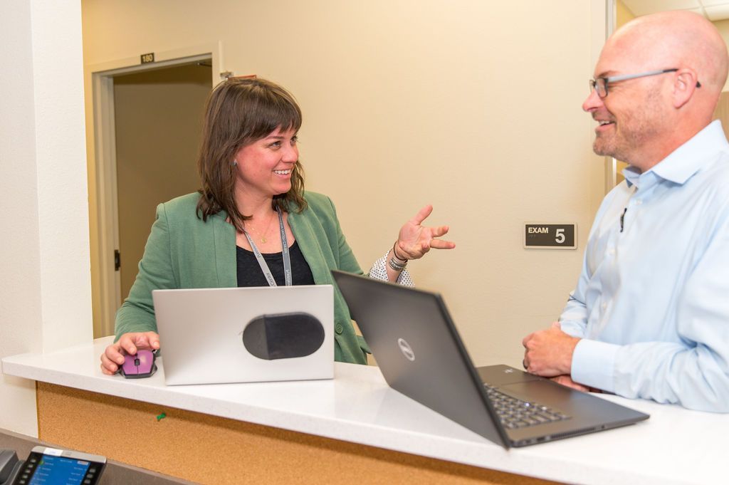 A man and a woman are sitting at a counter with laptops.