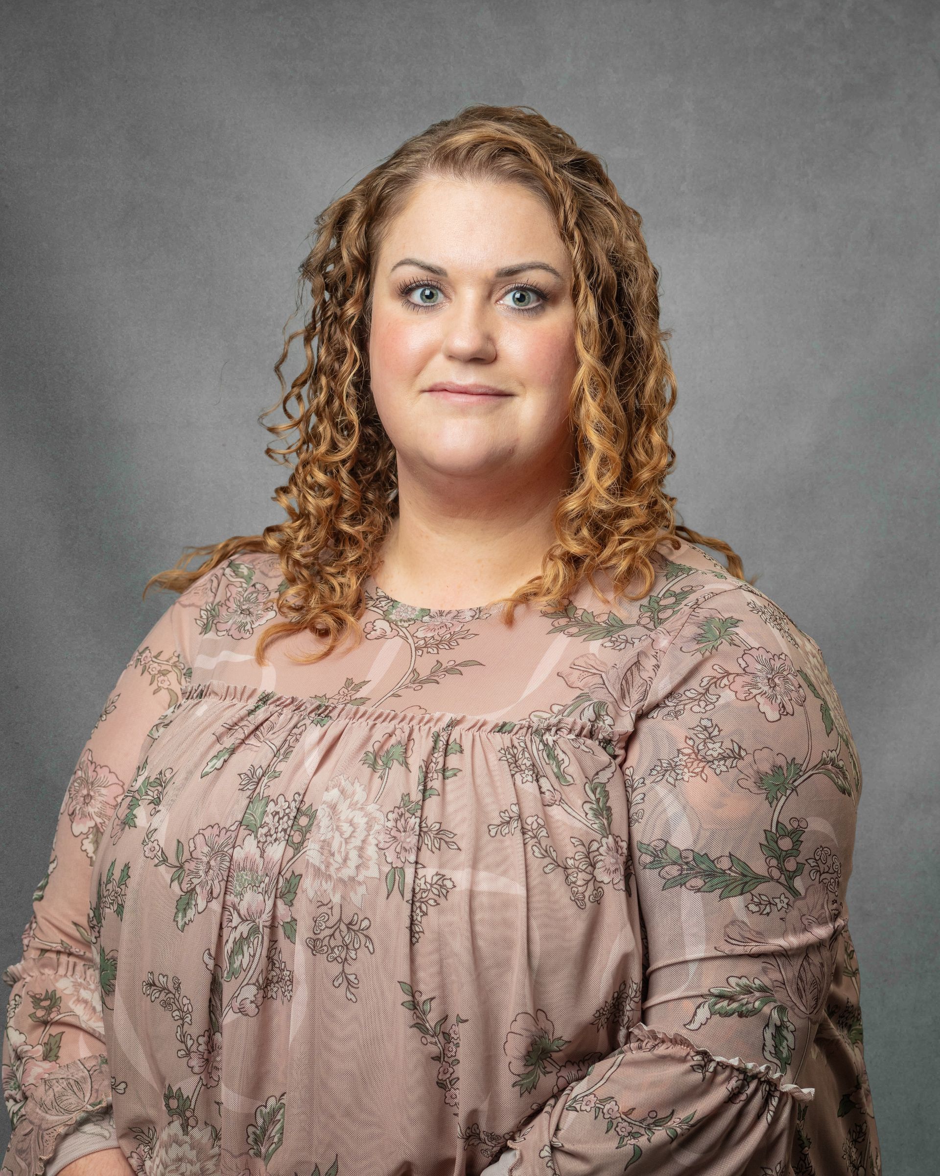 A woman wearing a denim jacket is smiling for the camera.