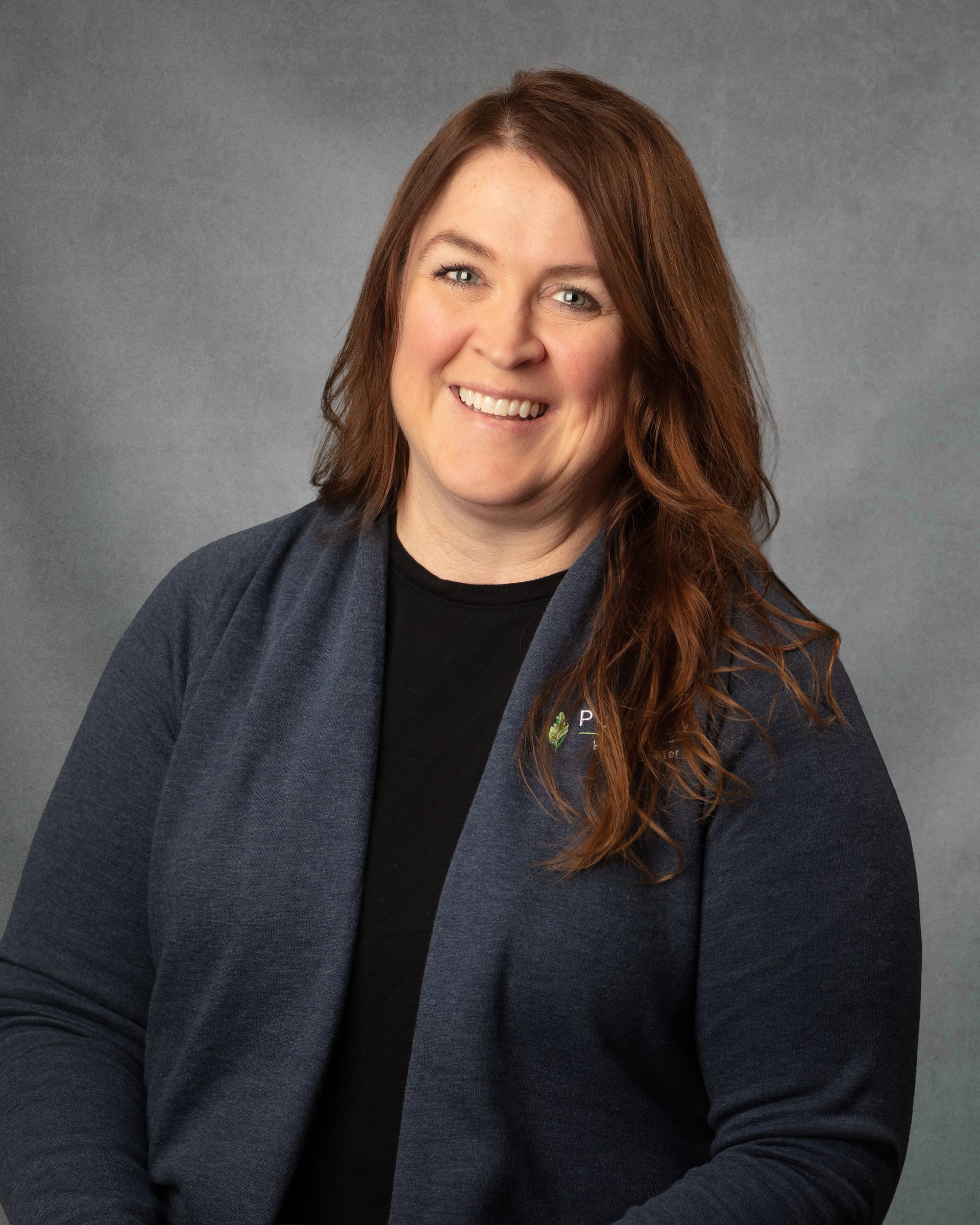 A woman with long brown hair is smiling for the camera.