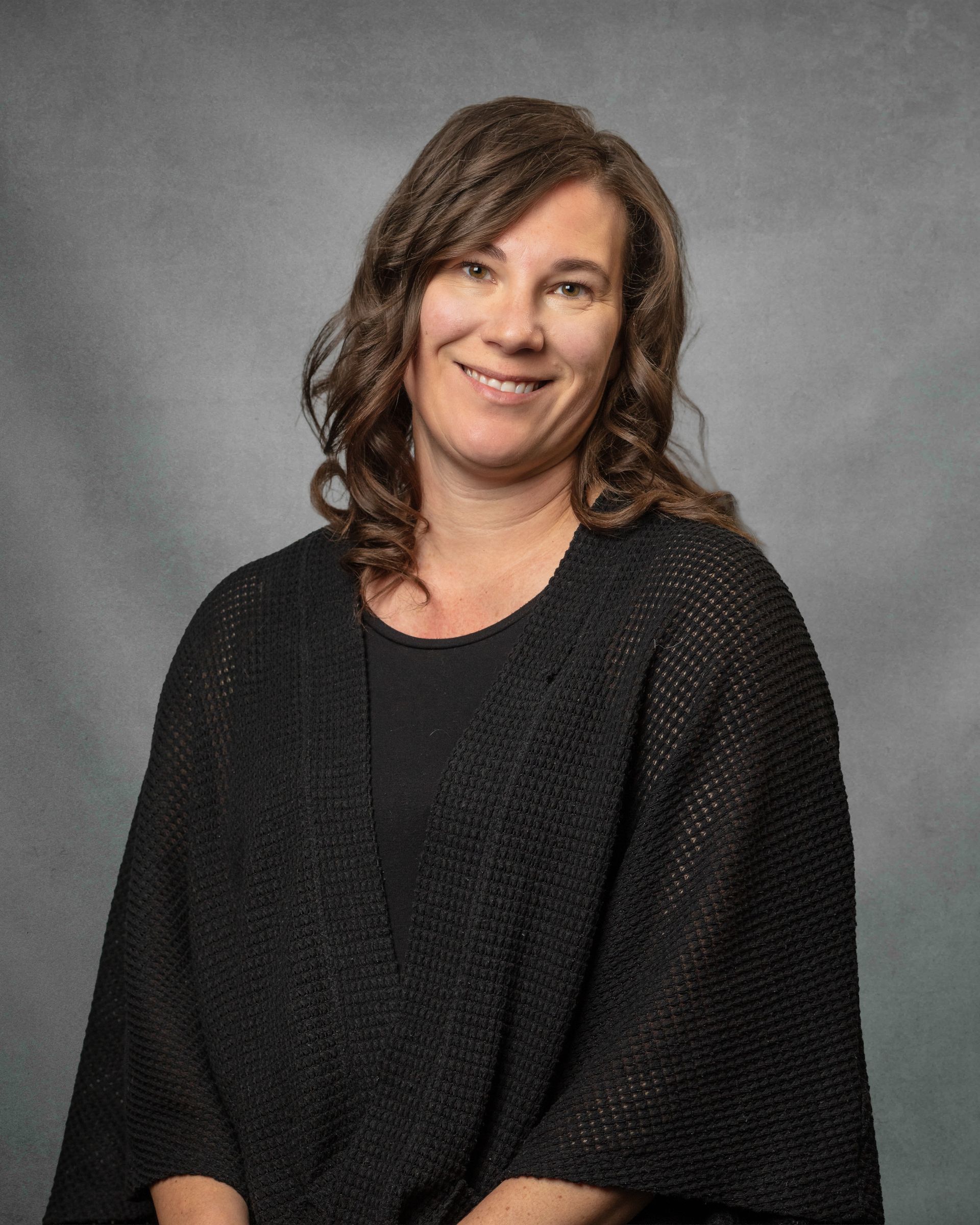 A woman in a black sweater is smiling for the camera