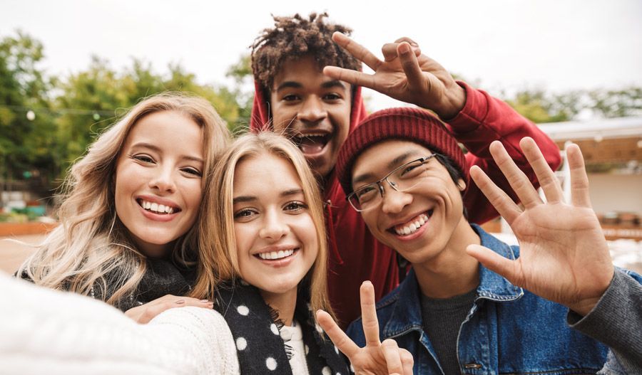 A group of young people are taking a selfie and giving a peace sign.