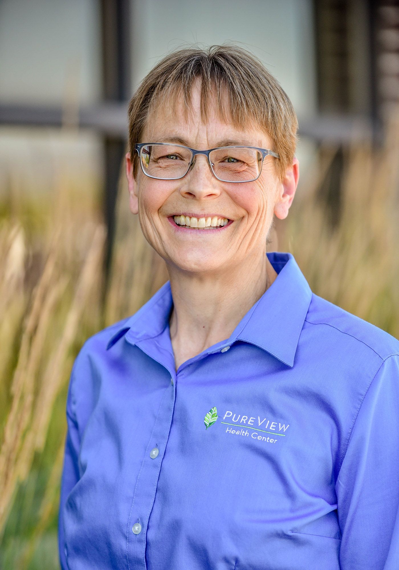 Joelle Selk. A woman wearing glasses and a blue shirt is smiling for the camera.