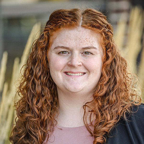 A woman with red curly hair and freckles is smiling for the camera.