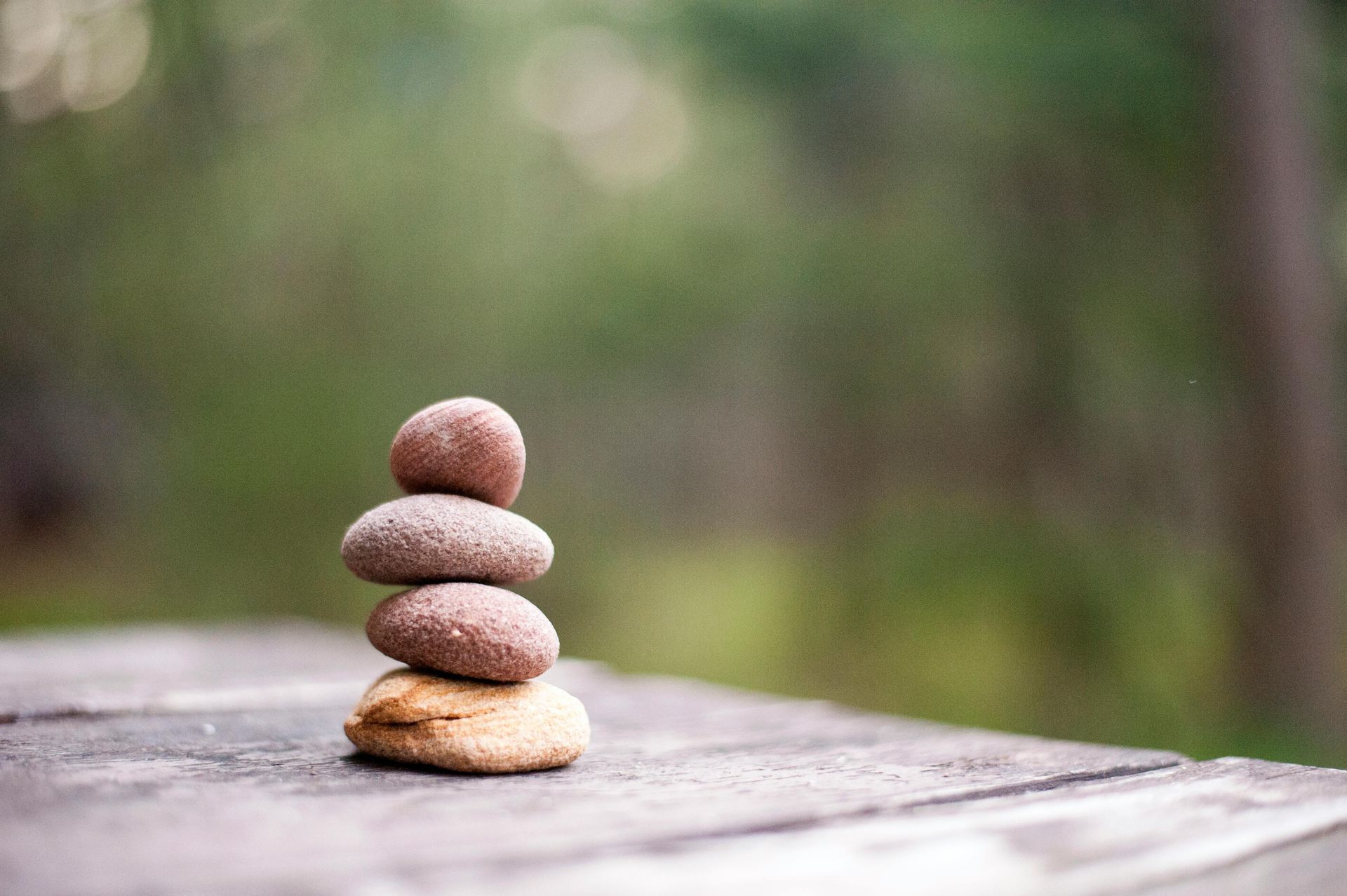 Three rocks are stacked on top of each other on a wooden table.