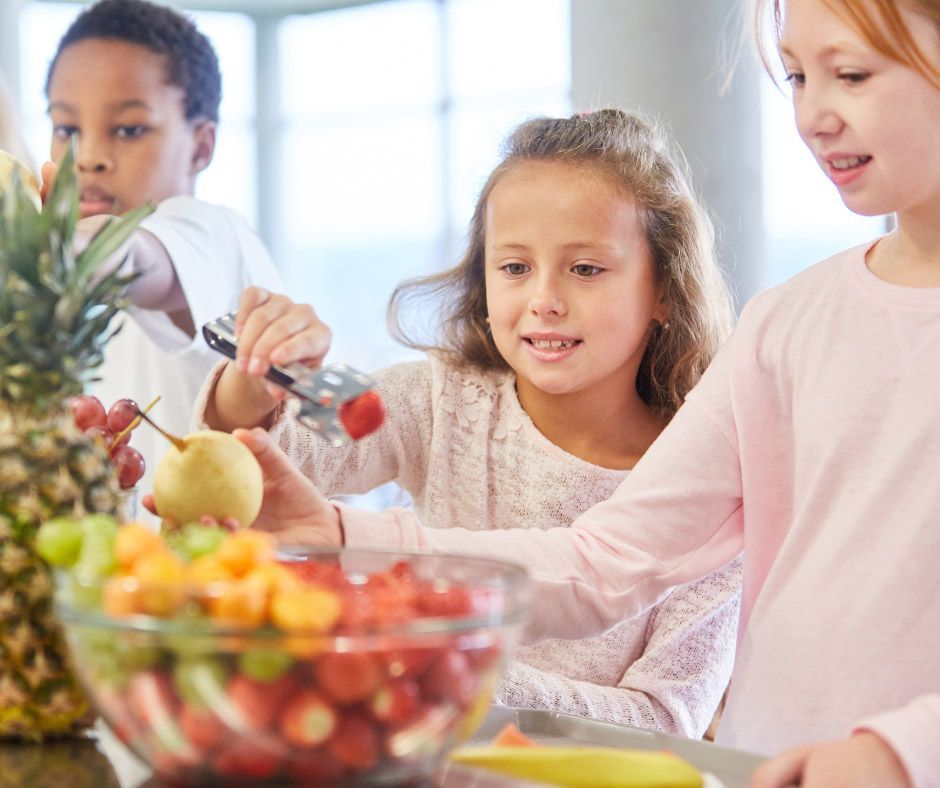 A group of children are preparing a fruit salad in a kitchen.
