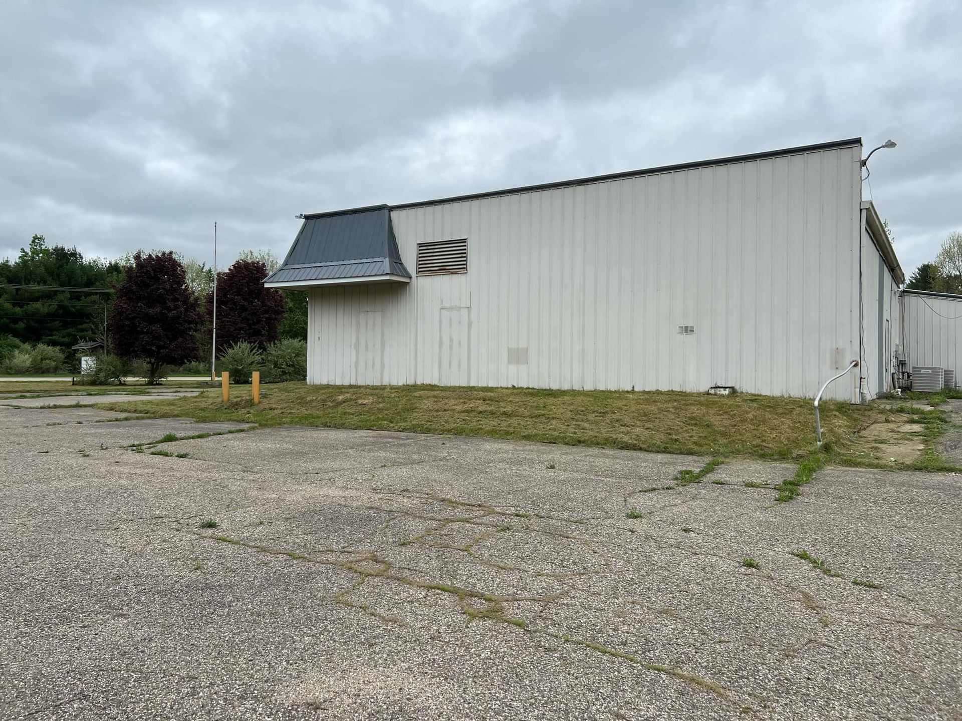 A large white building is sitting on top of a gravel lot.