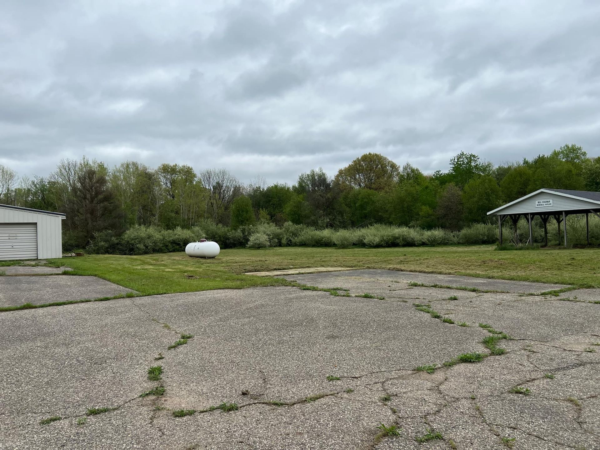 There is a propane tank in the middle of a grassy field.
