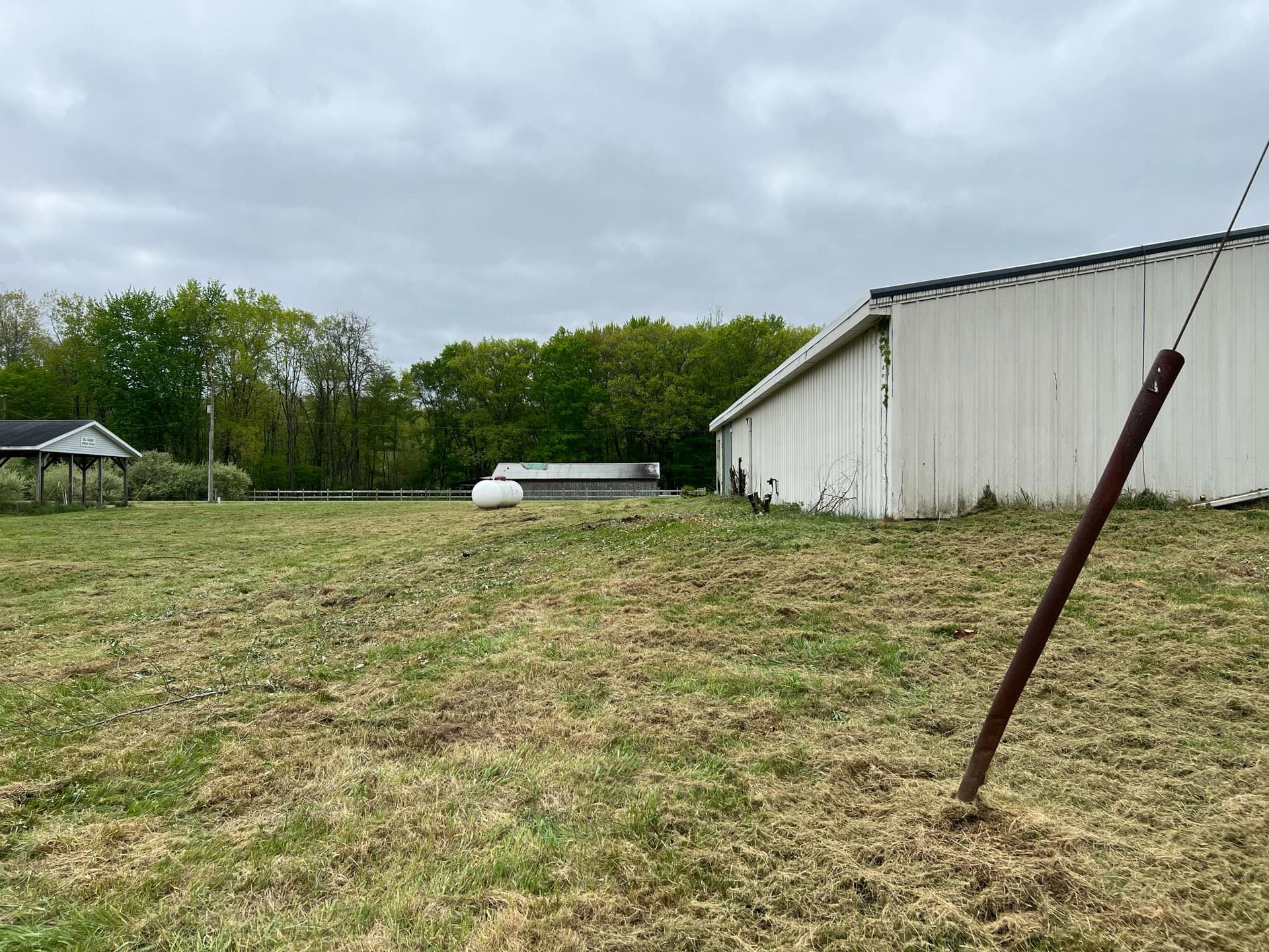 A large white building is sitting in the middle of a grassy field.