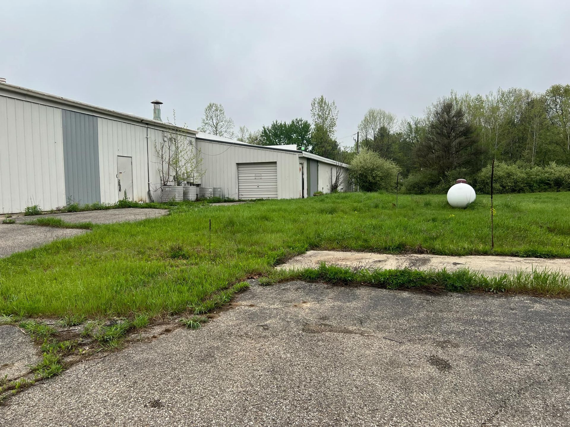 A large white ball is sitting in the middle of a grassy field in front of a building.