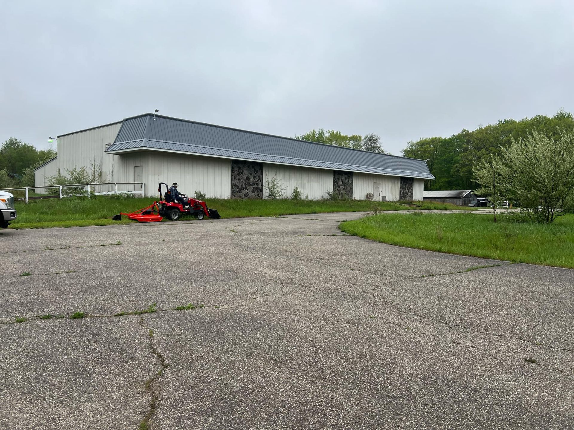 A lawn mower is parked in front of a large building.