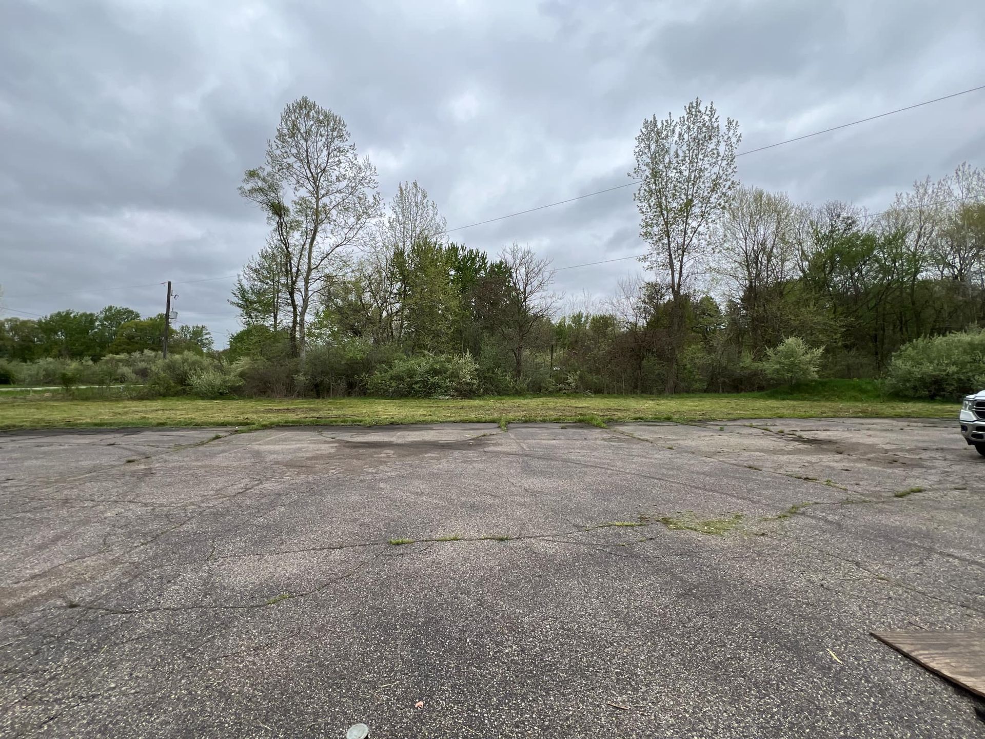 A car is parked in a parking lot with trees in the background.