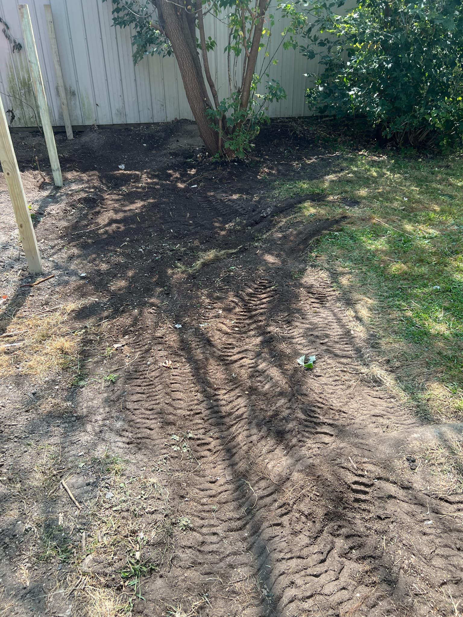 There are tire tracks in the dirt in the backyard.