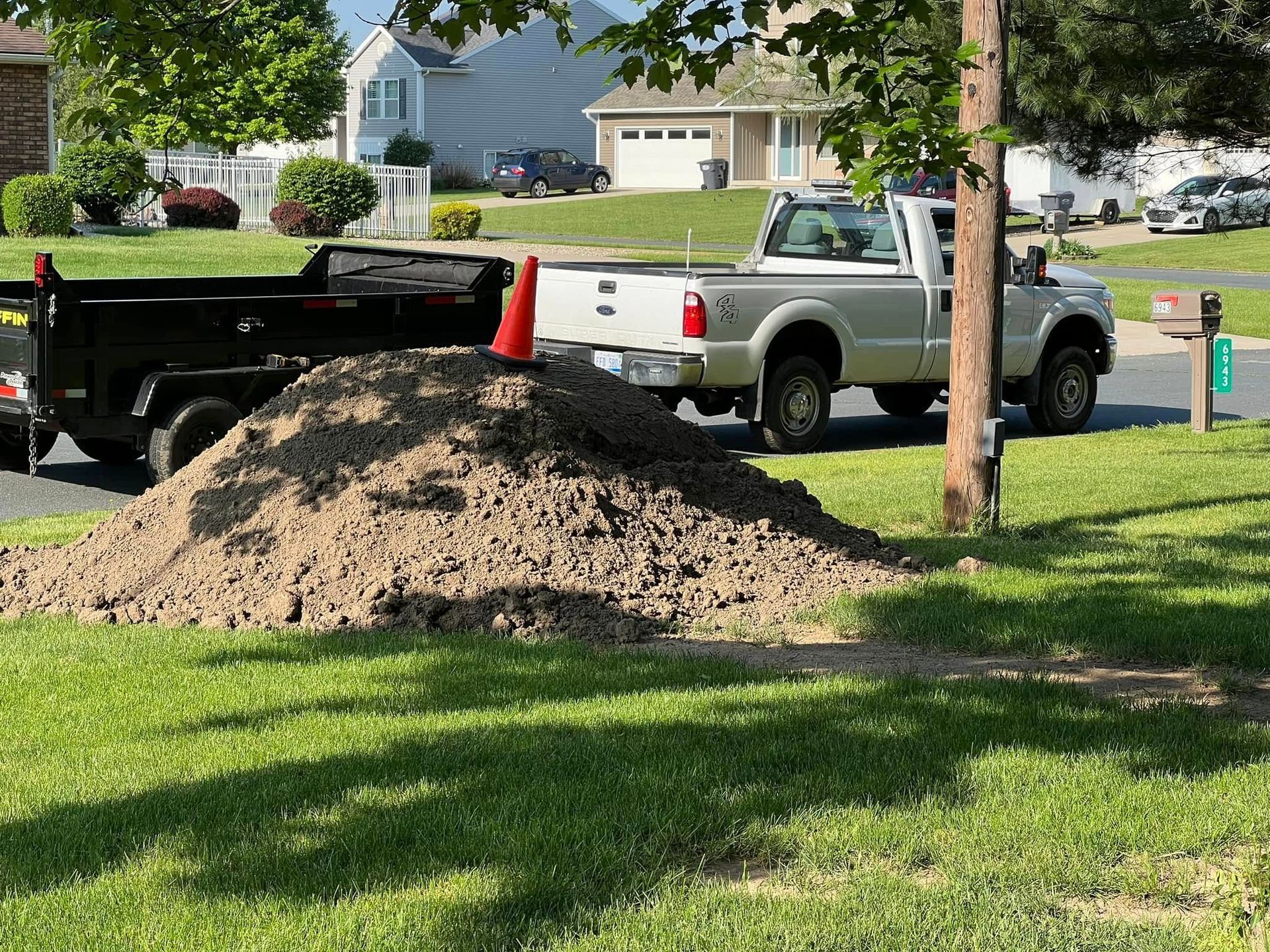 A white truck is parked next to a pile of dirt.