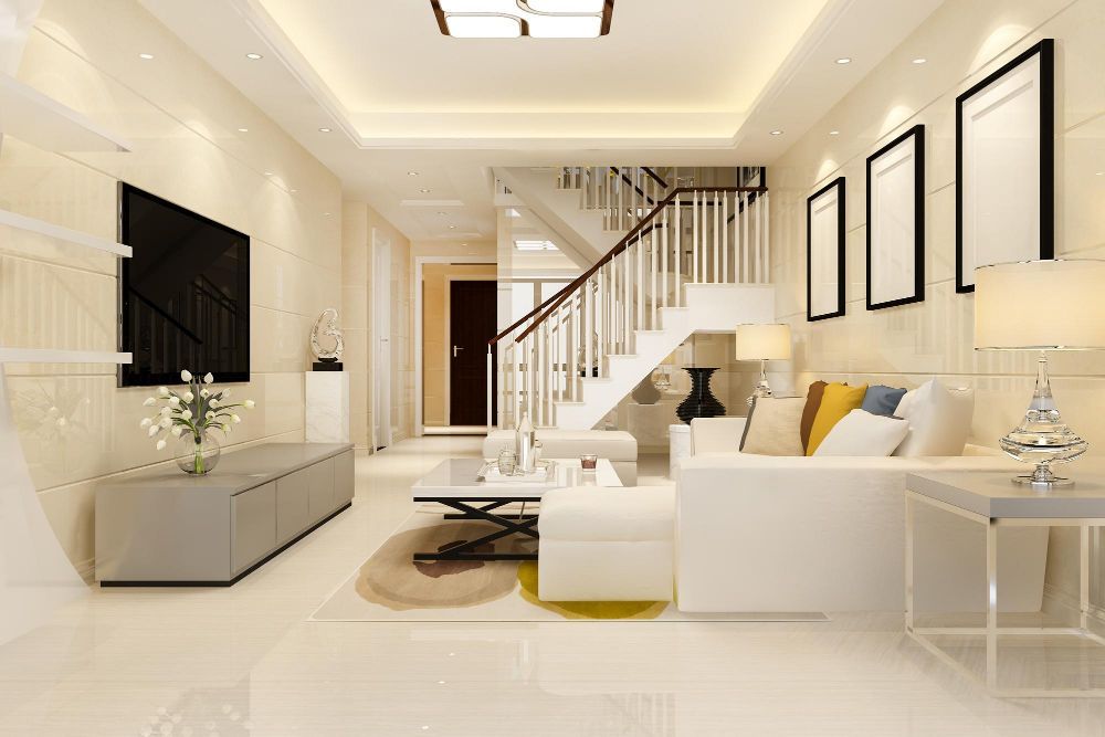 Spacious white living room with staircase, sofa, TV, and framed art; cream walls and flooring.
