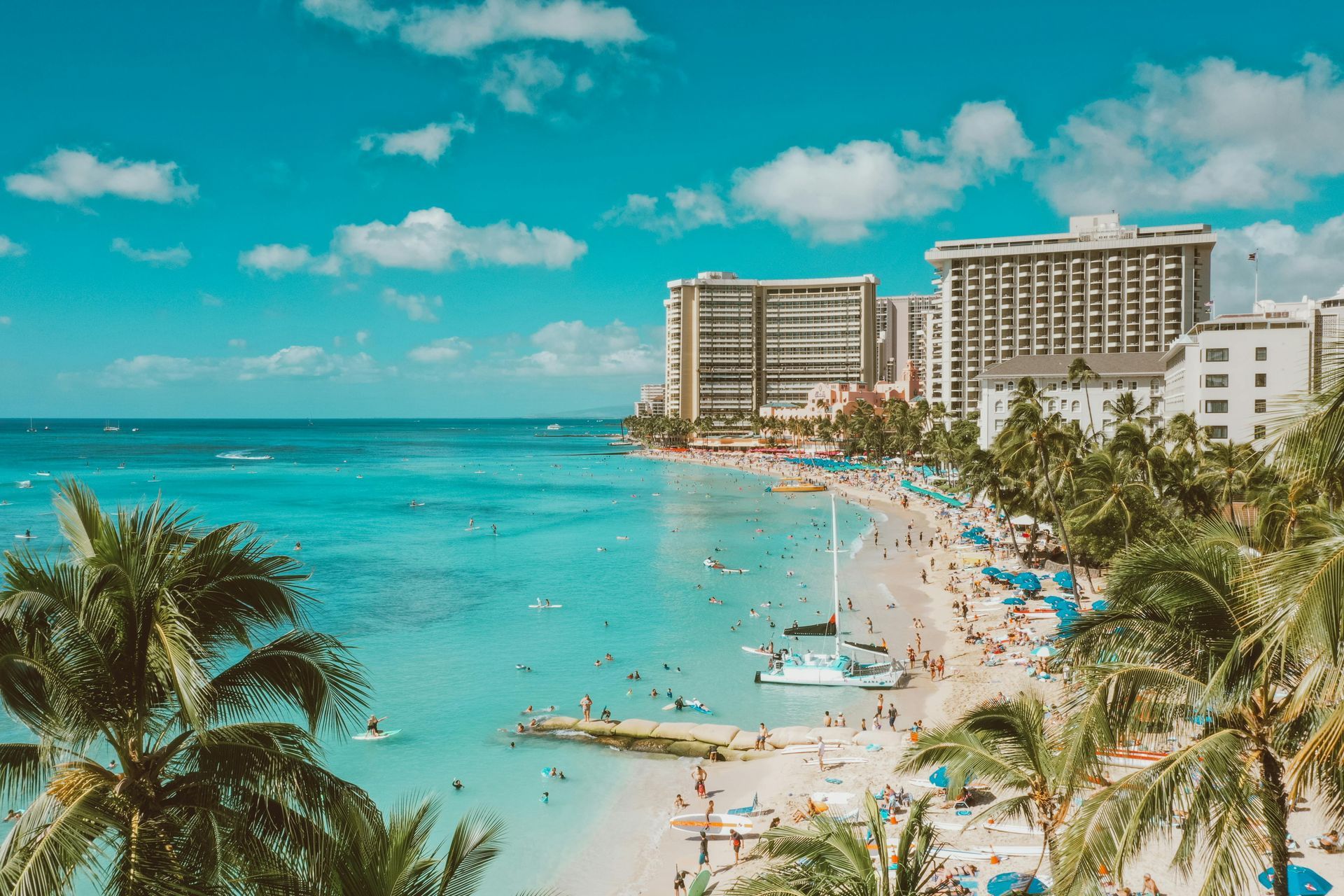 Aerial view of a large house with a tile roof, pool, and surrounding trees.