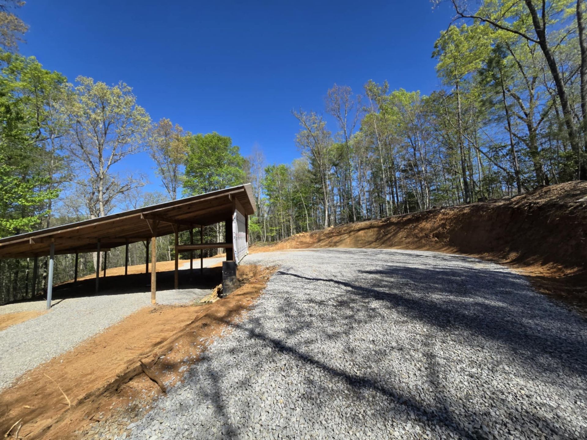A gravel road with a wooden shelter on the side of it.