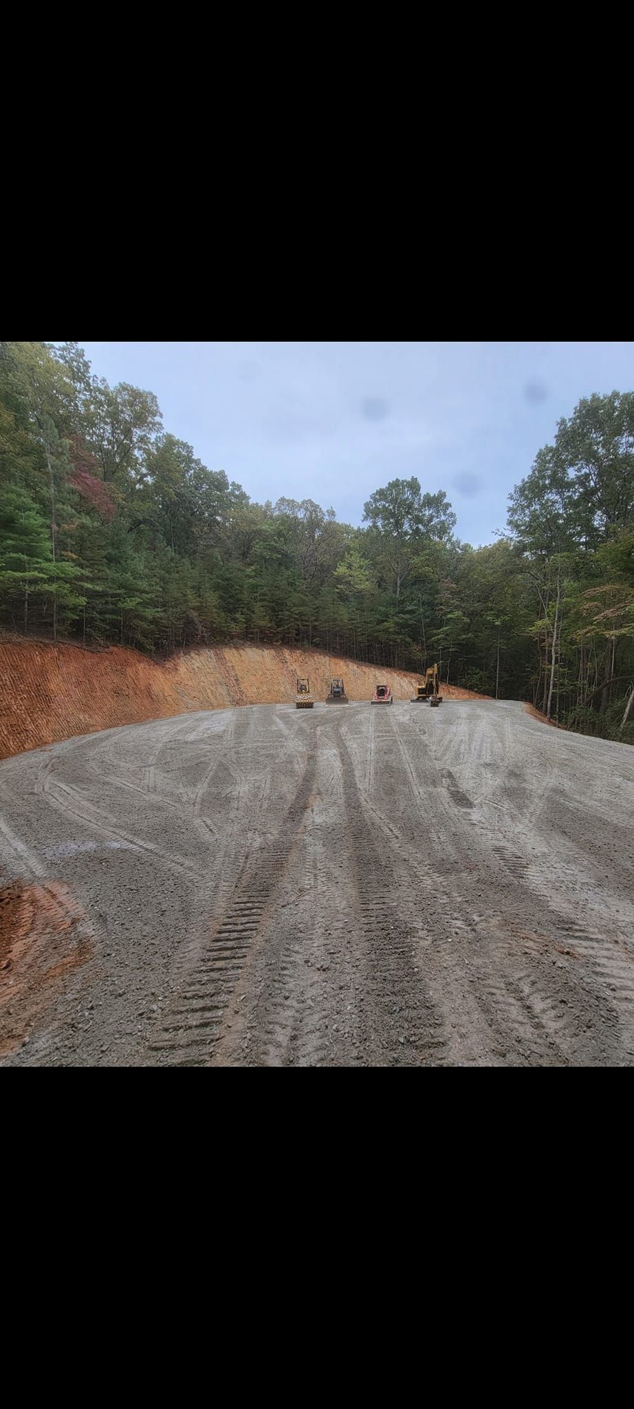 A dirt road going through a forest with trees on both sides.