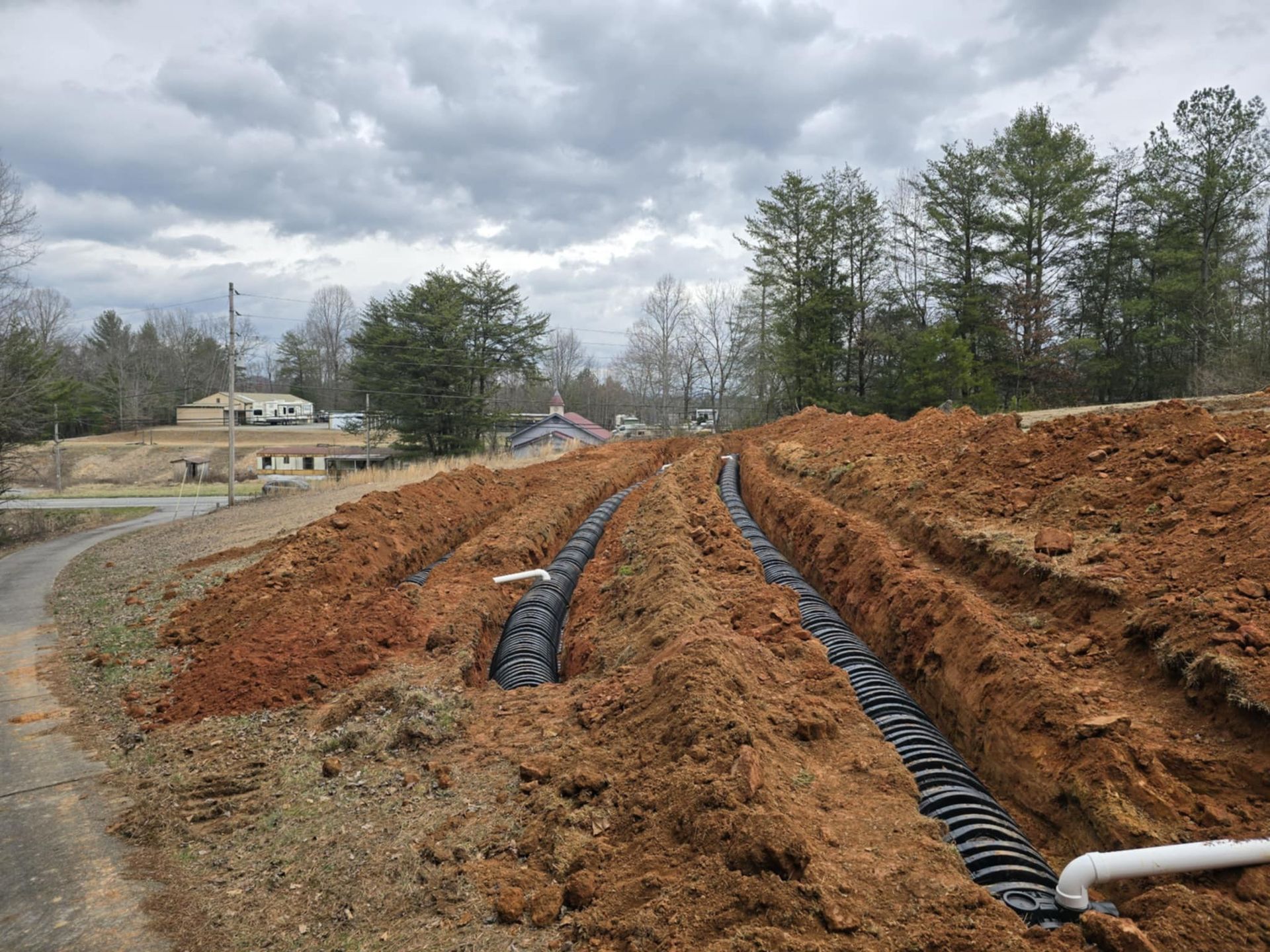 A drainage system is being installed in a dirt field.