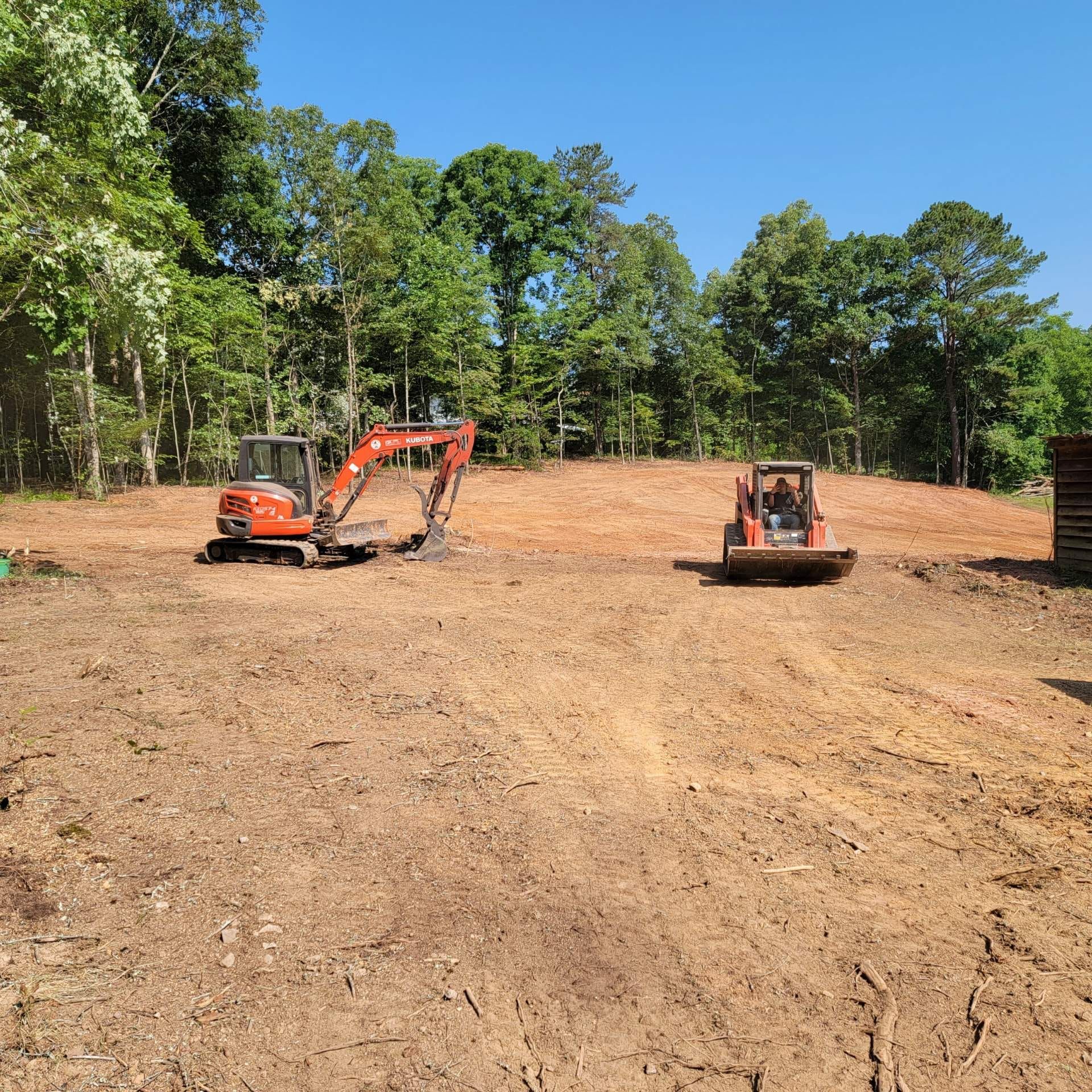 A couple of tractors are sitting on top of a dirt field.