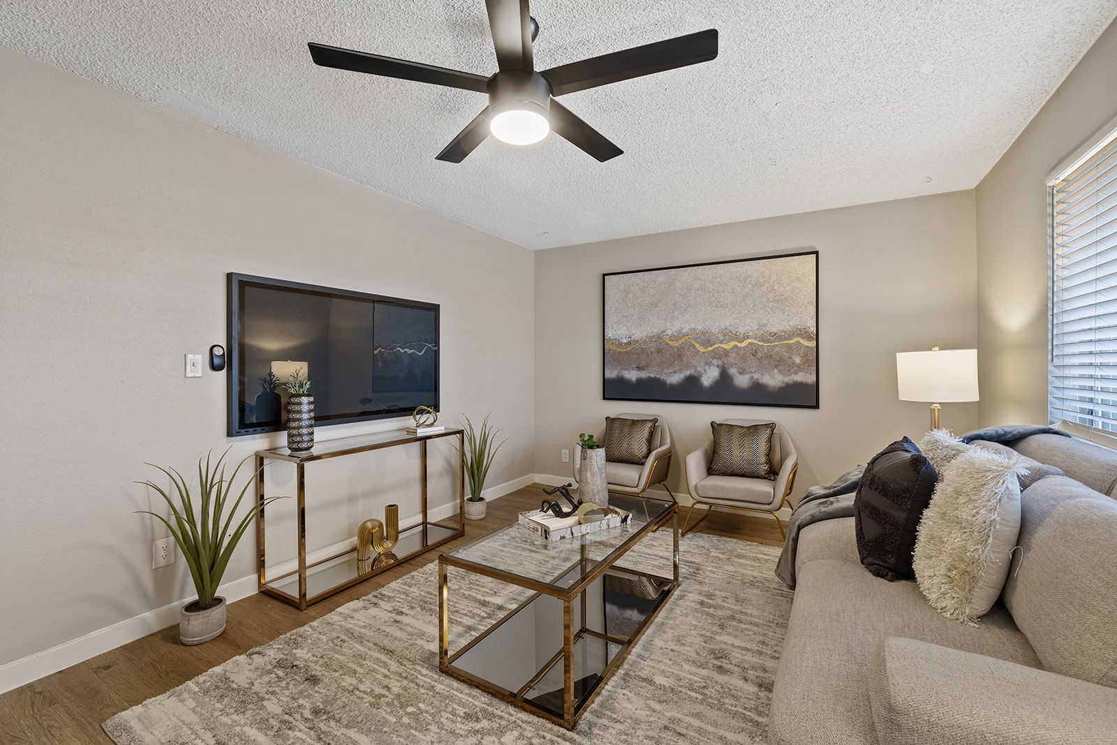 Living room with couch, coffee table, TV, and artwork. Neutral colors, modern style.