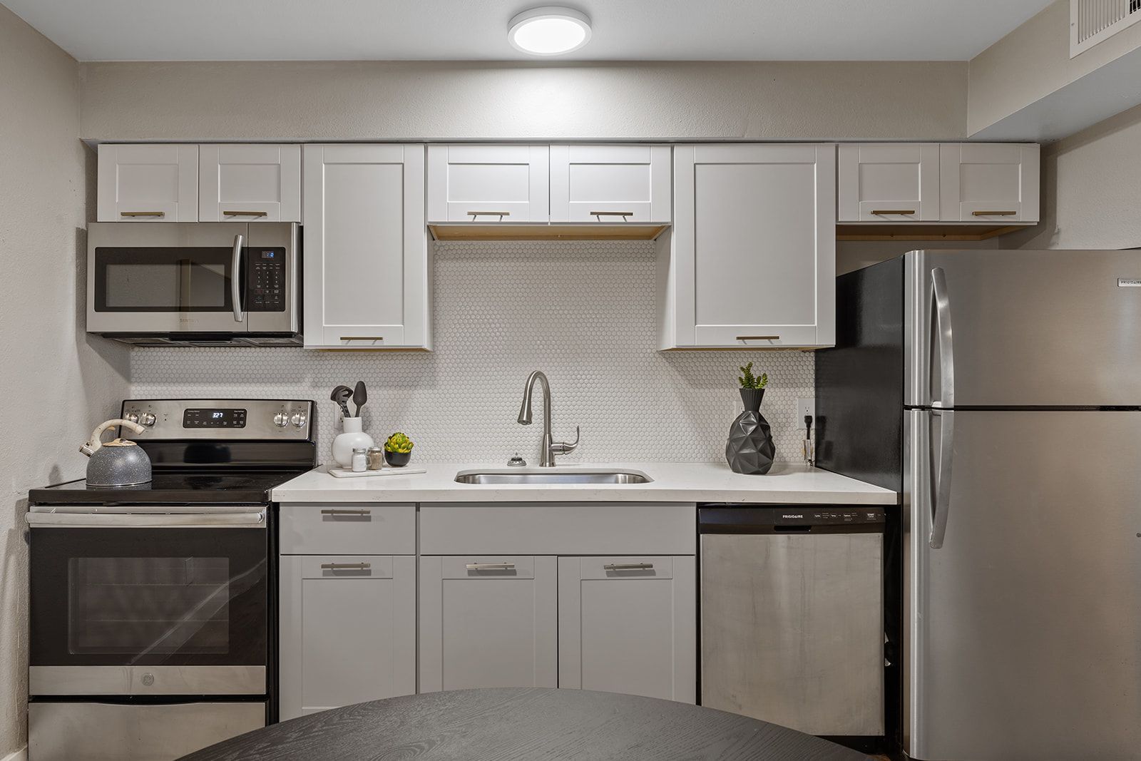 Kitchen with light gray cabinets, stainless steel appliances, and white backsplash.
