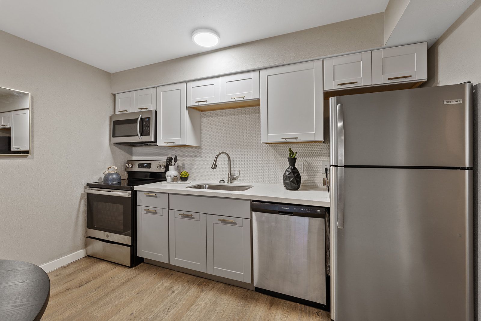Modern kitchen with stainless steel appliances, light gray cabinets, and a white backsplash.