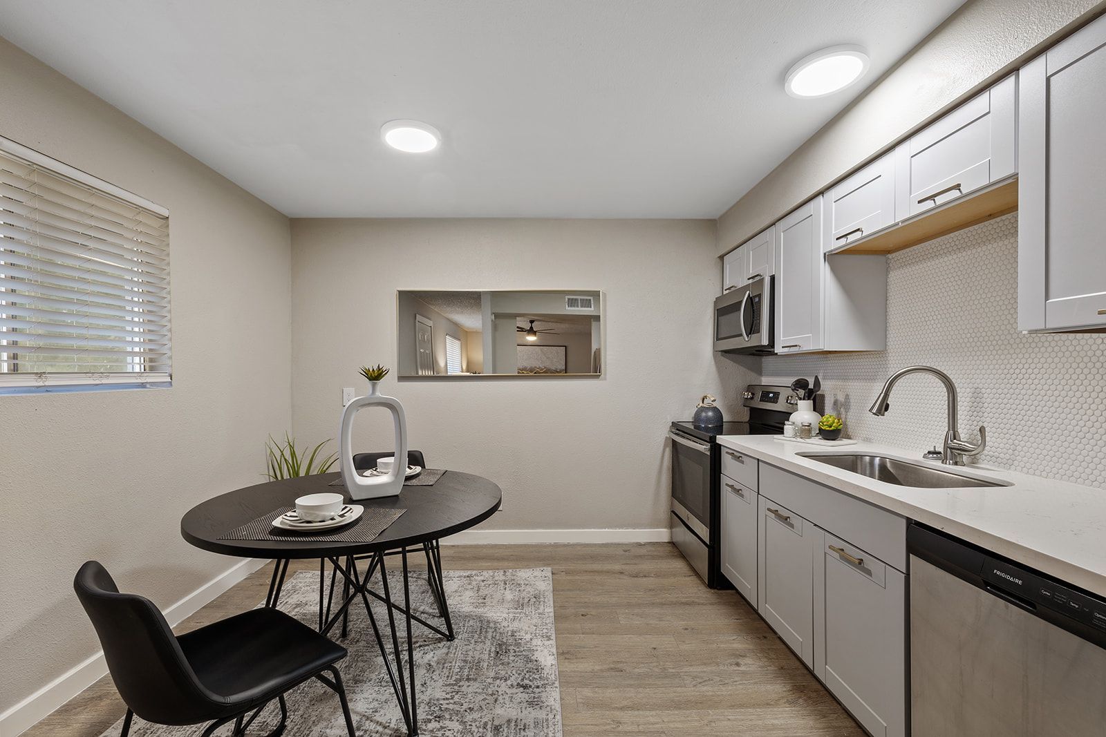 Kitchen with gray cabinets, stainless steel appliances, and a black dining table.