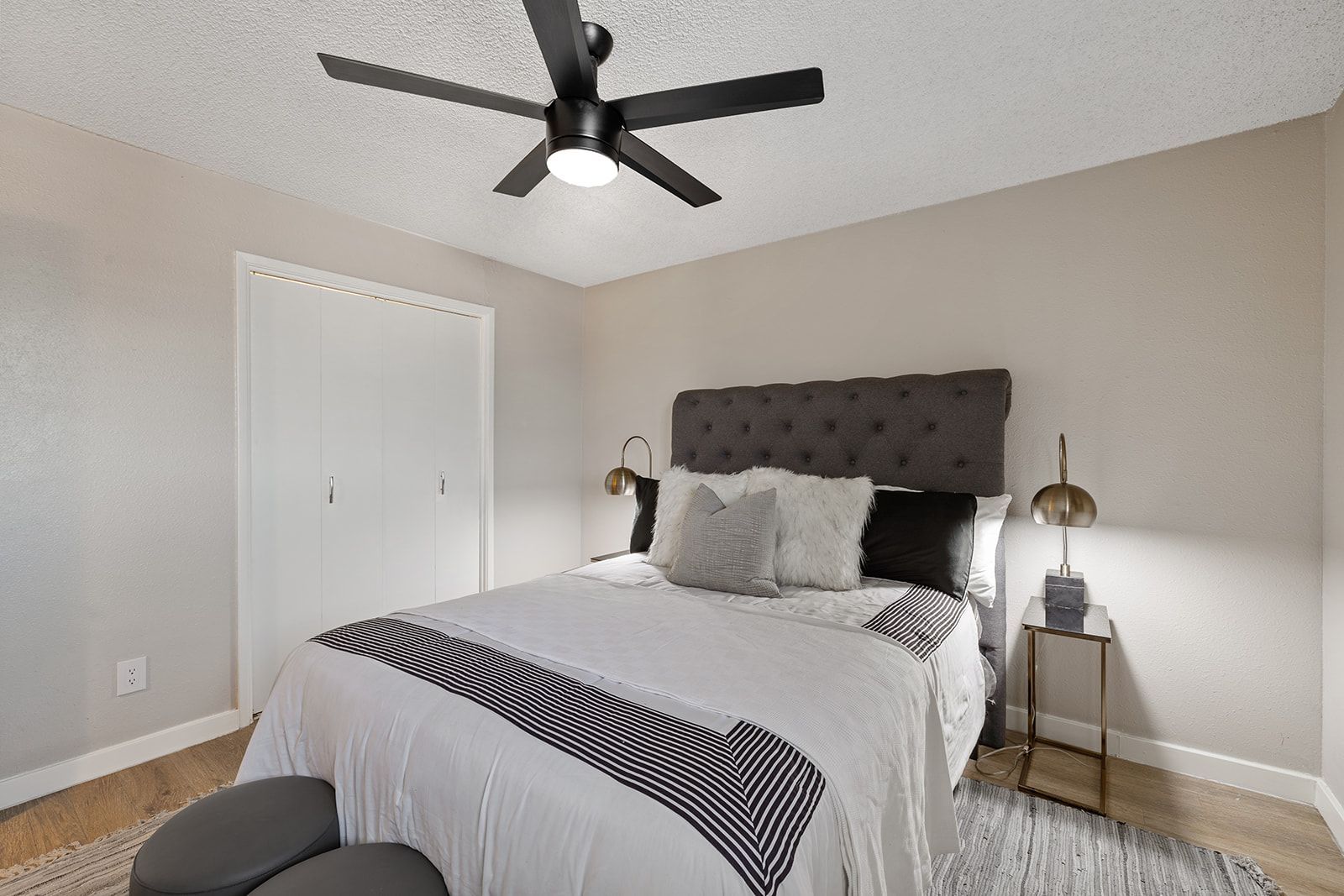 Bedroom with bed, dark headboard, ceiling fan, and bedside tables.