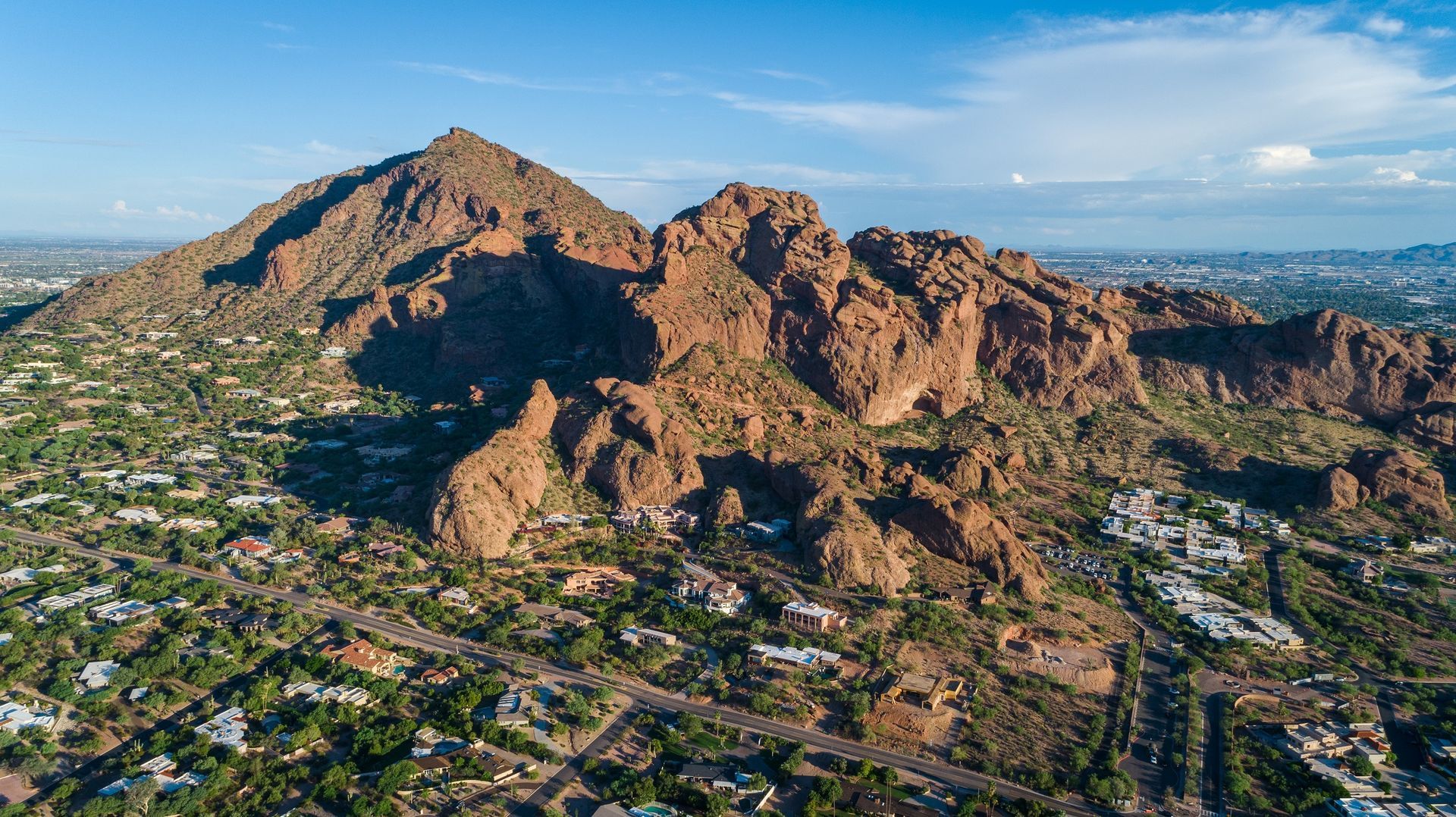 Brown mountains and surrounding residences under a blue sky in Phoenix, Arizona.