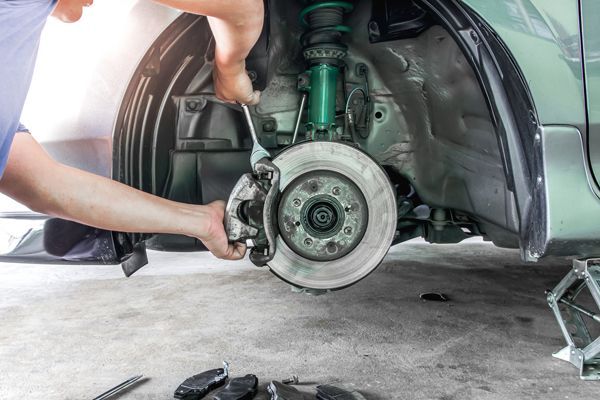 Auto mechanic providing professional brake service and maintenance on a vehicle’s disk brakes.