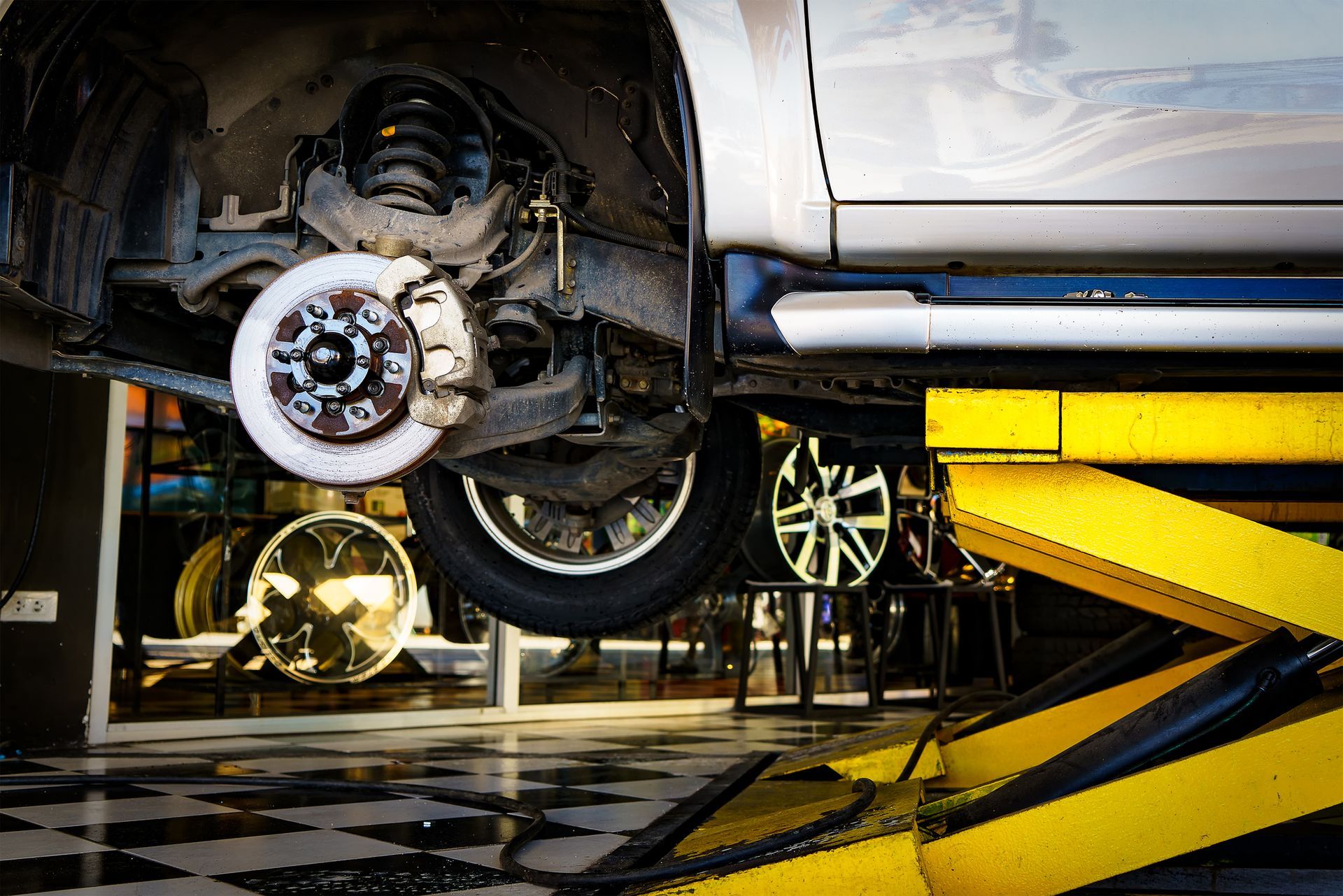 Car mechanics changing tire at auto repair shop garage.