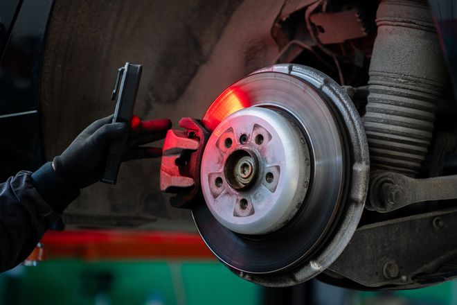 Close up of hands of serviceman checking the brake discs of a car. Close up of hands of serviceman checking the brake discs of a car.